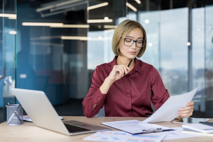 Businesswoman analyzing documents and charts in modern office