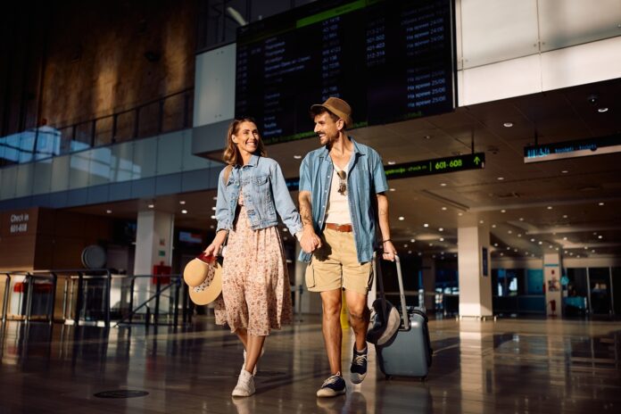 Happy couple walking through airport while traveling on summer vacation.